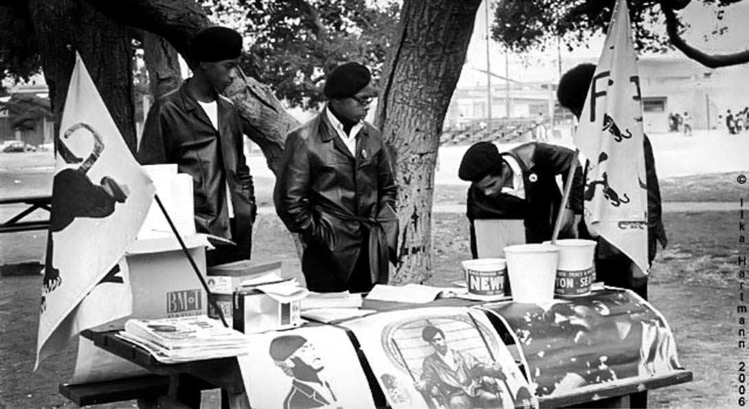 four people in berets and leather jackets standing at a booth table for the Black Panther Party