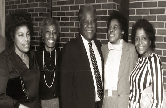 black and white photograph of five people posing for a picture