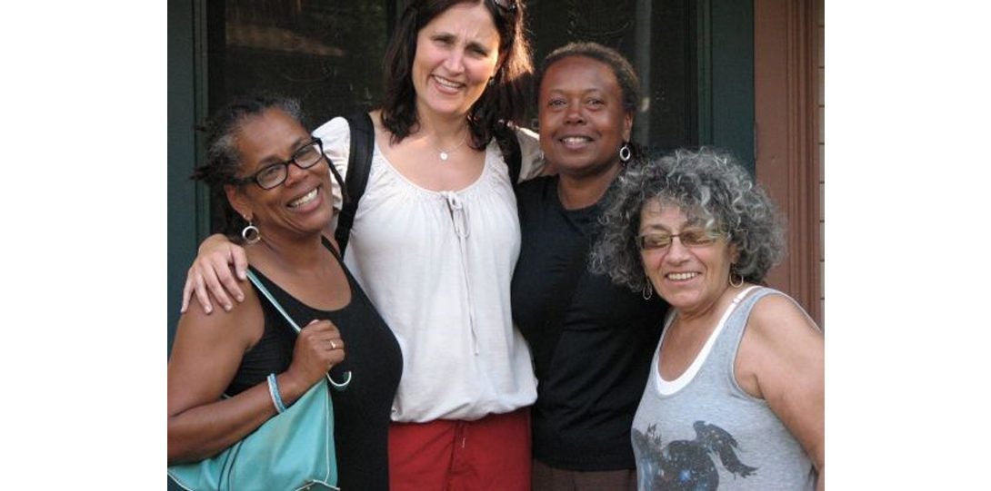 four people embracing while posing for a photograph