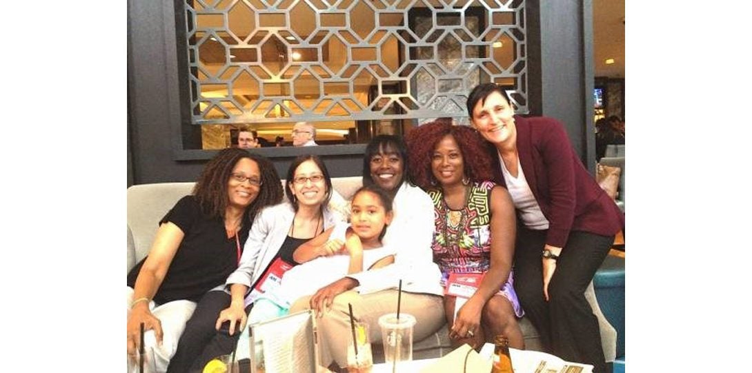 five adults and a child posing together for a photograph seated in front a table with drinks