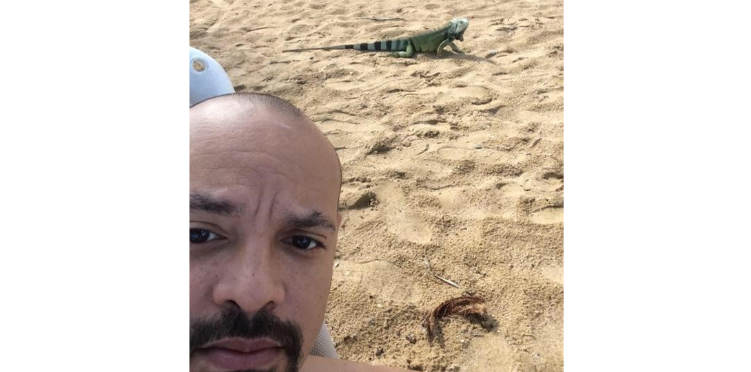 Professor Johnson taking a selfie with lizard in background on sand