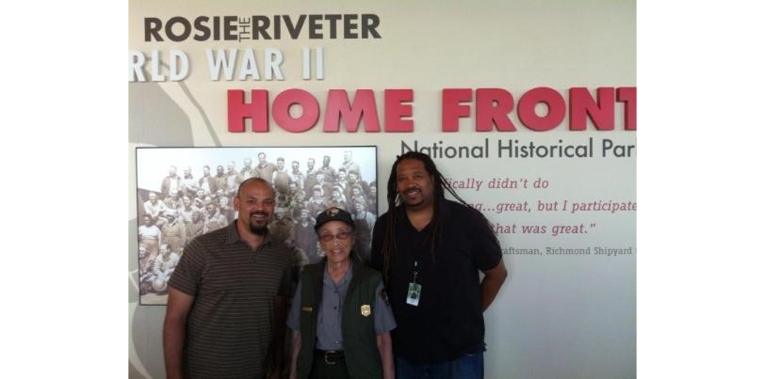 Professor Johnson standing with two others in front of the sign for Rosie the Riveter World War II Home Front National Park