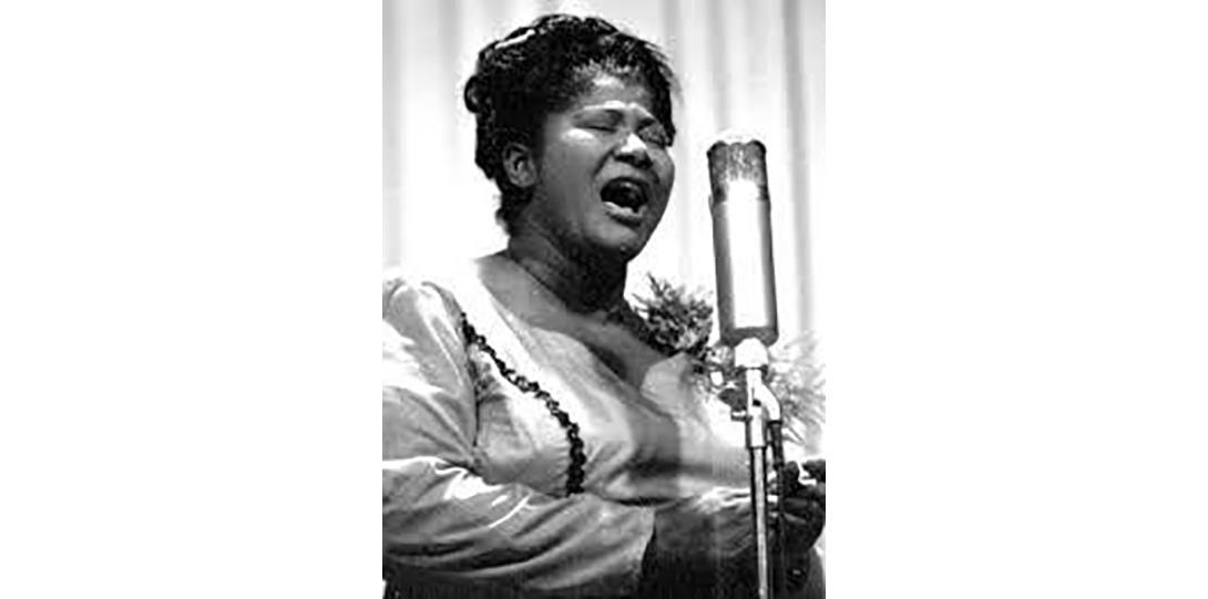 Mahalia Jackson singing with eyes closed in front of microphone
