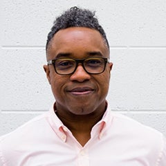 person posing for photograph in front of white concrete wall