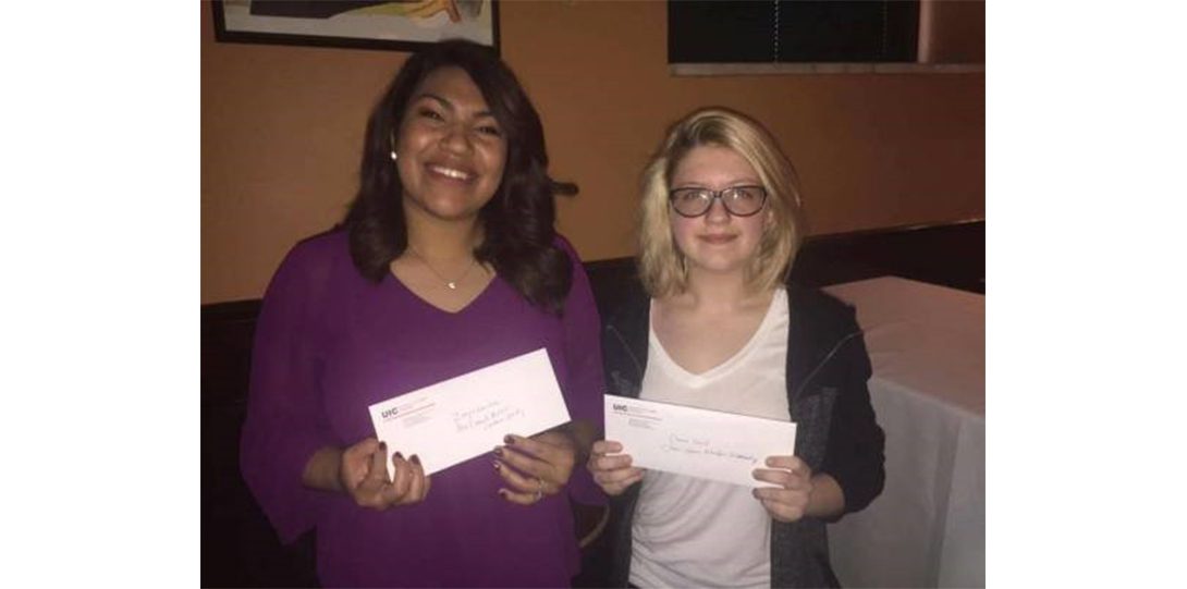 two students holding white envelopes posing for photograph