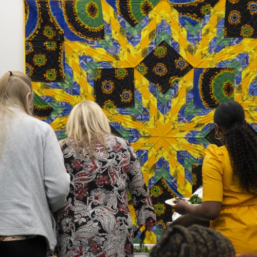 Students standing in front of a quilt