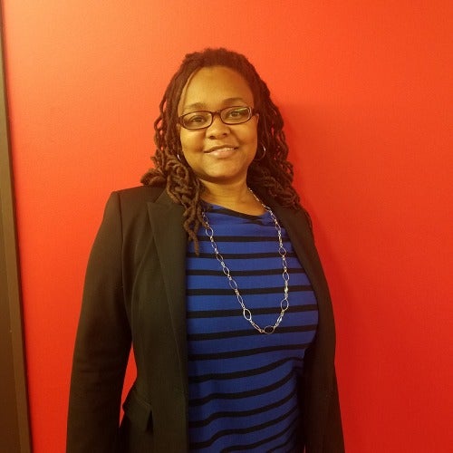 person posing for a photograph in front of a red wall