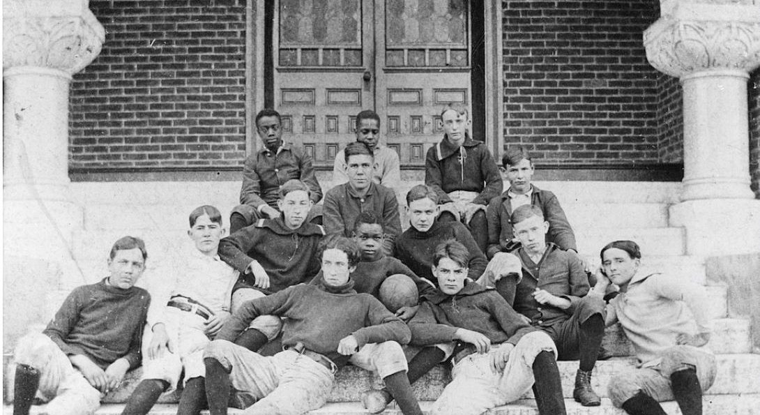 Young football players pose for a photo on the steps of a building entrance