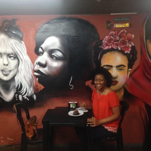 Prof. Harrington sitting at a table in front of a mural of four people