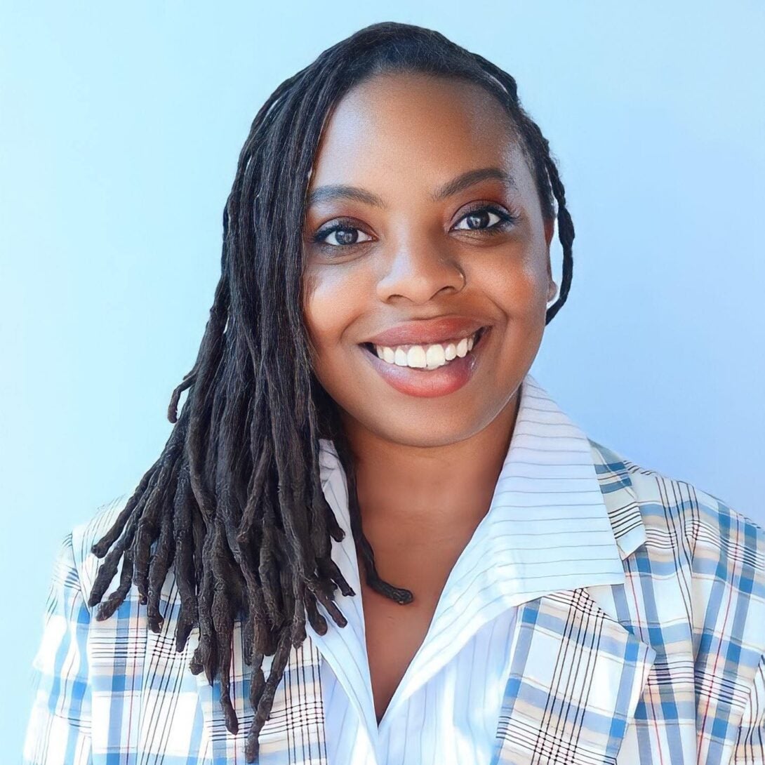 person wearing a blue checkered shirt smiling at the camera