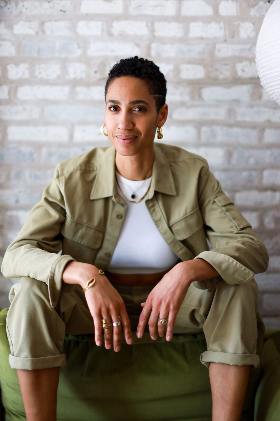 person wearing a green and white outfit sitting on a green chair and looking at the camera