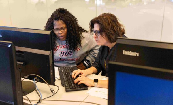 two people looking at a computer and working together