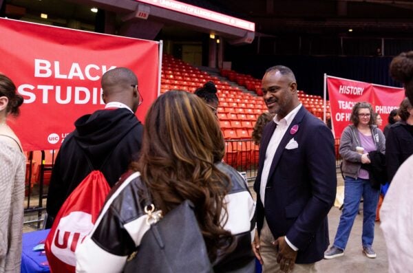 professor wearing a button talking to prospective students next to a banner that says black studies