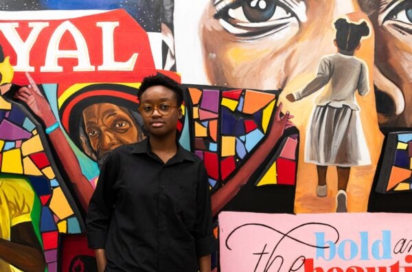 student standing in front of a wall covered in an art collage