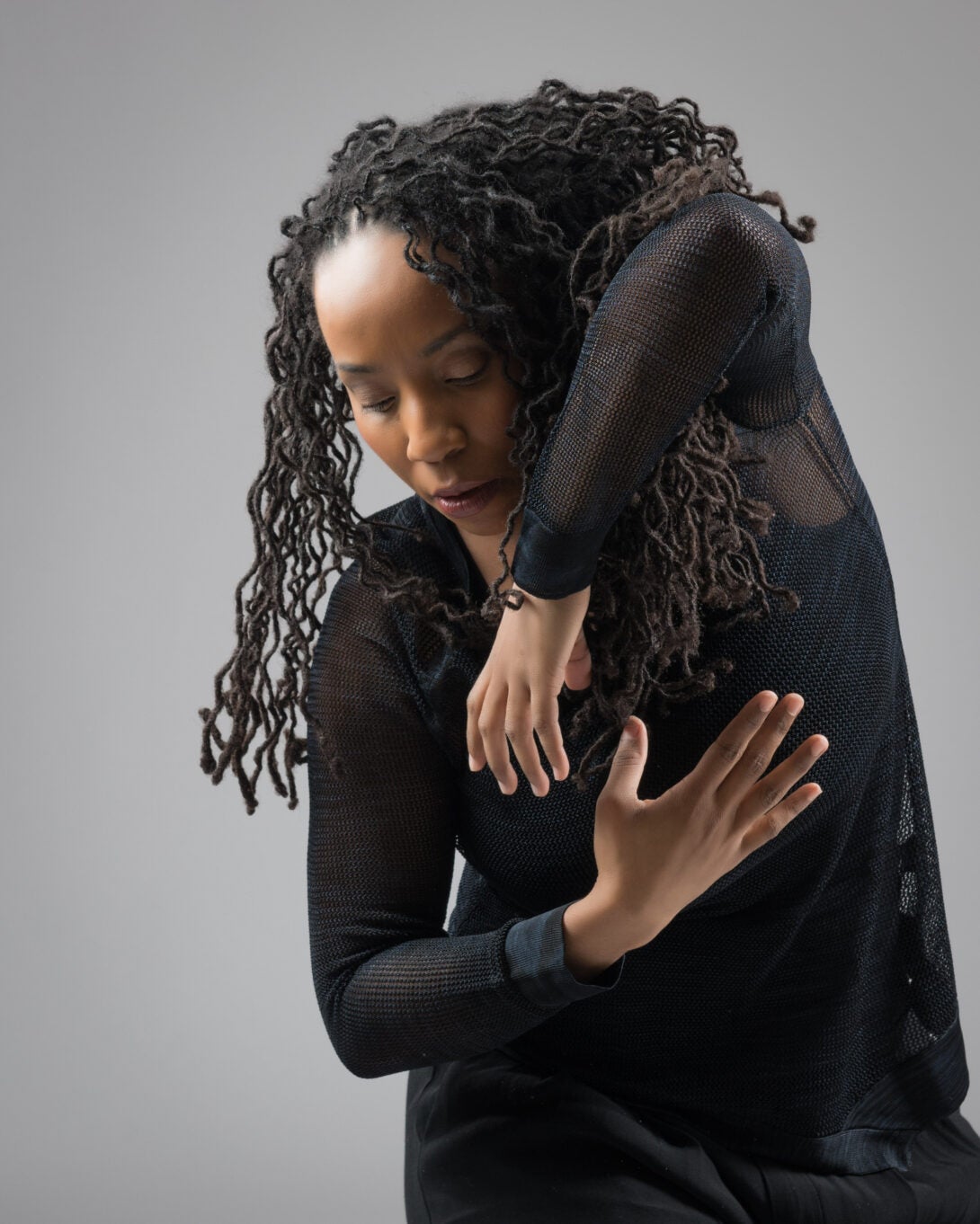 woman with locs looking down and cuffing arms