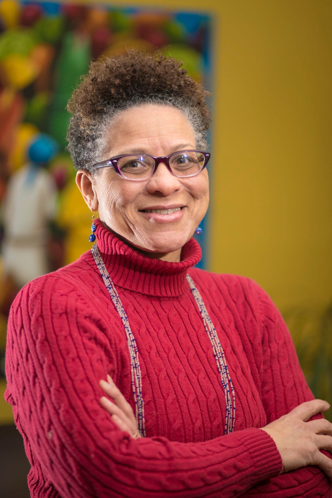 woman with glasses and red turtle neck sweater smiling at camera