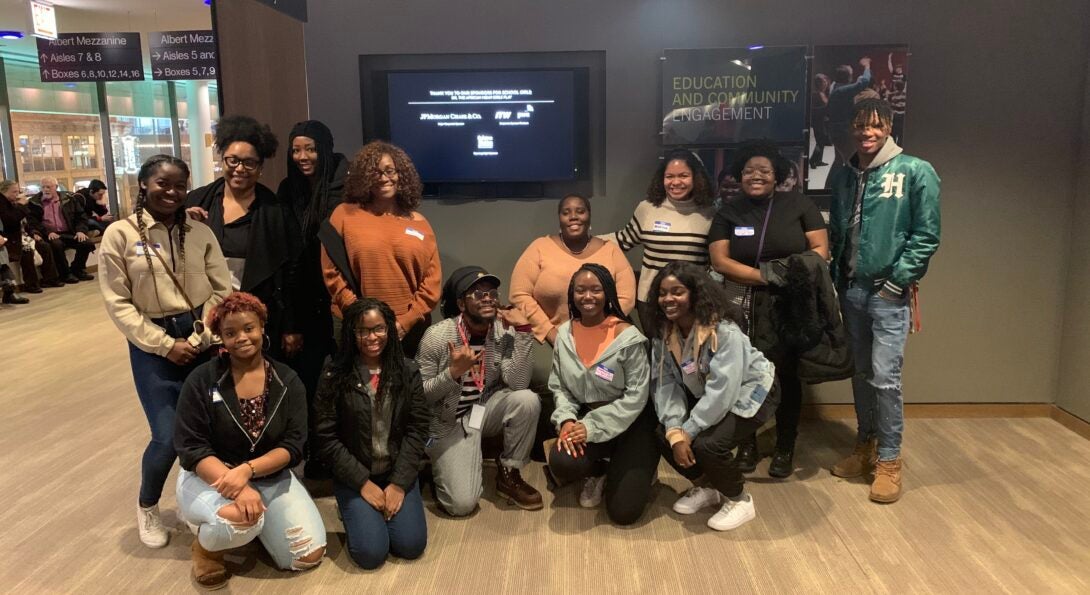 group of students sitting and standing together outside of a theater auditorium