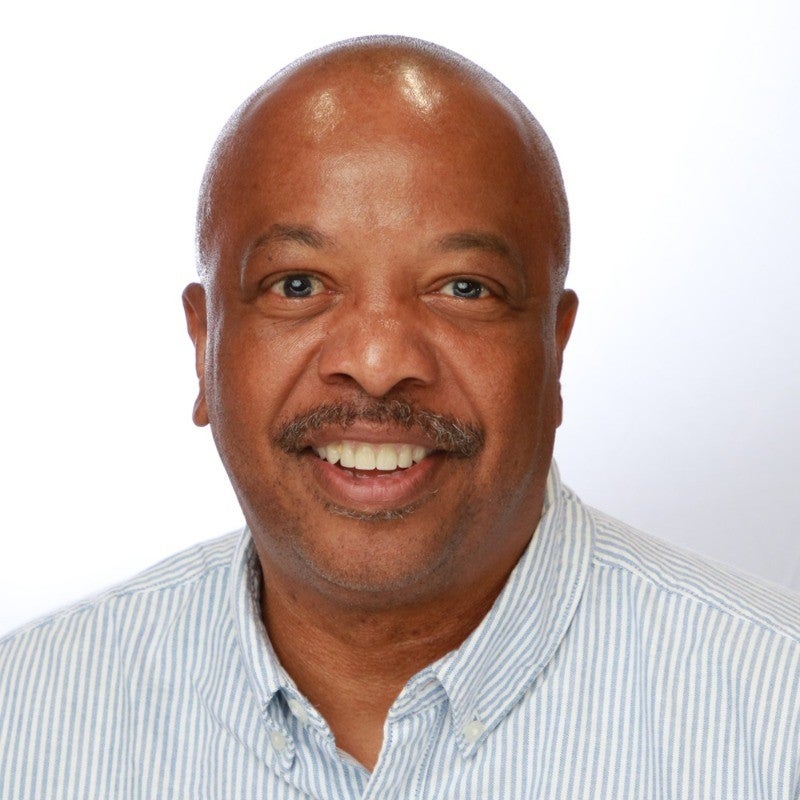 man with striped shirt smiling in headshot with white background