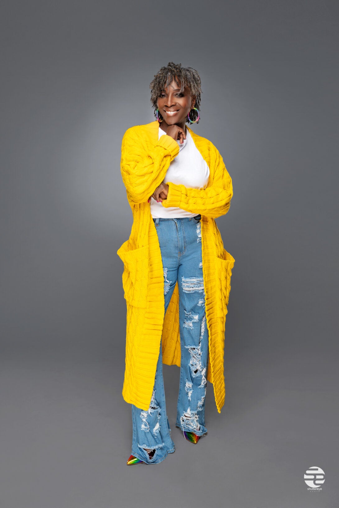 smiling woman standing in jeans and yellow sweater