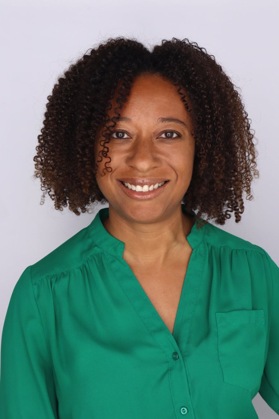 woman with green button up shirt smiling at the camera