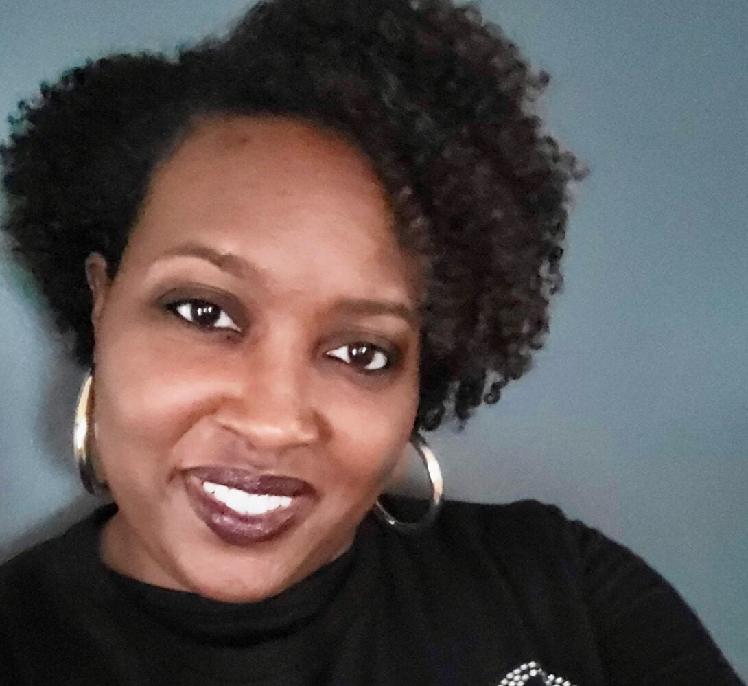 woman wearing black smiling at the camera and wearing gold earrings