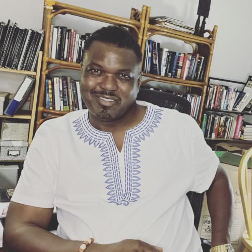 man in white shirt smiling at camera with books in background