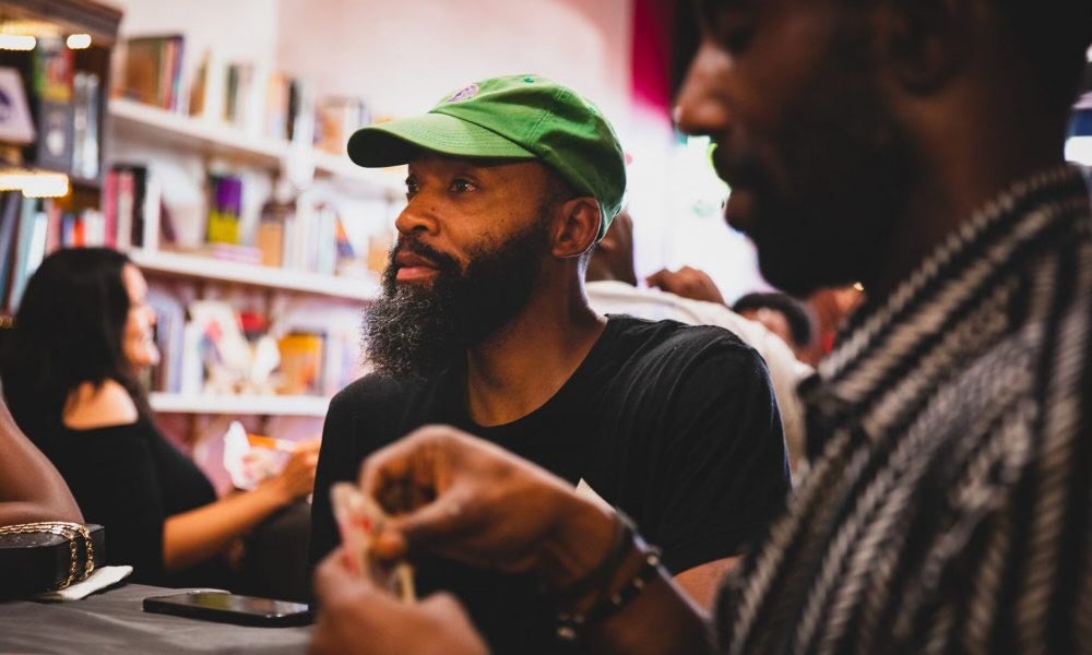 bearded man with green baseball cap and black shirt looking away from camera