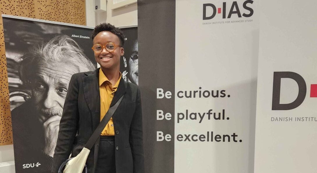 person standing in front of a banner at a conference wearing business attire