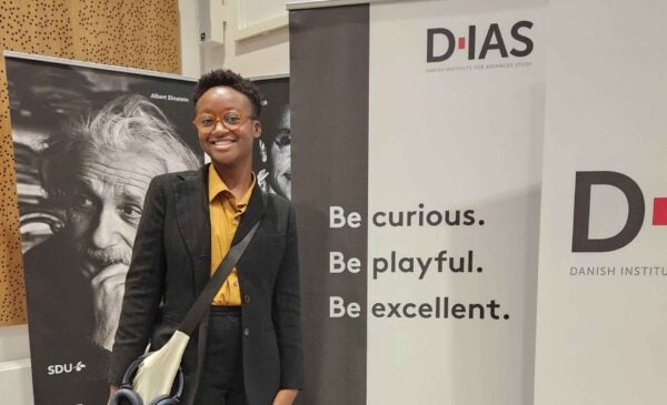 person standing in front of a banner at a conference wearing business attire