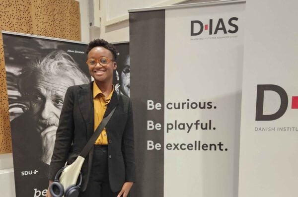 person standing in front of a banner at a conference wearing business attire