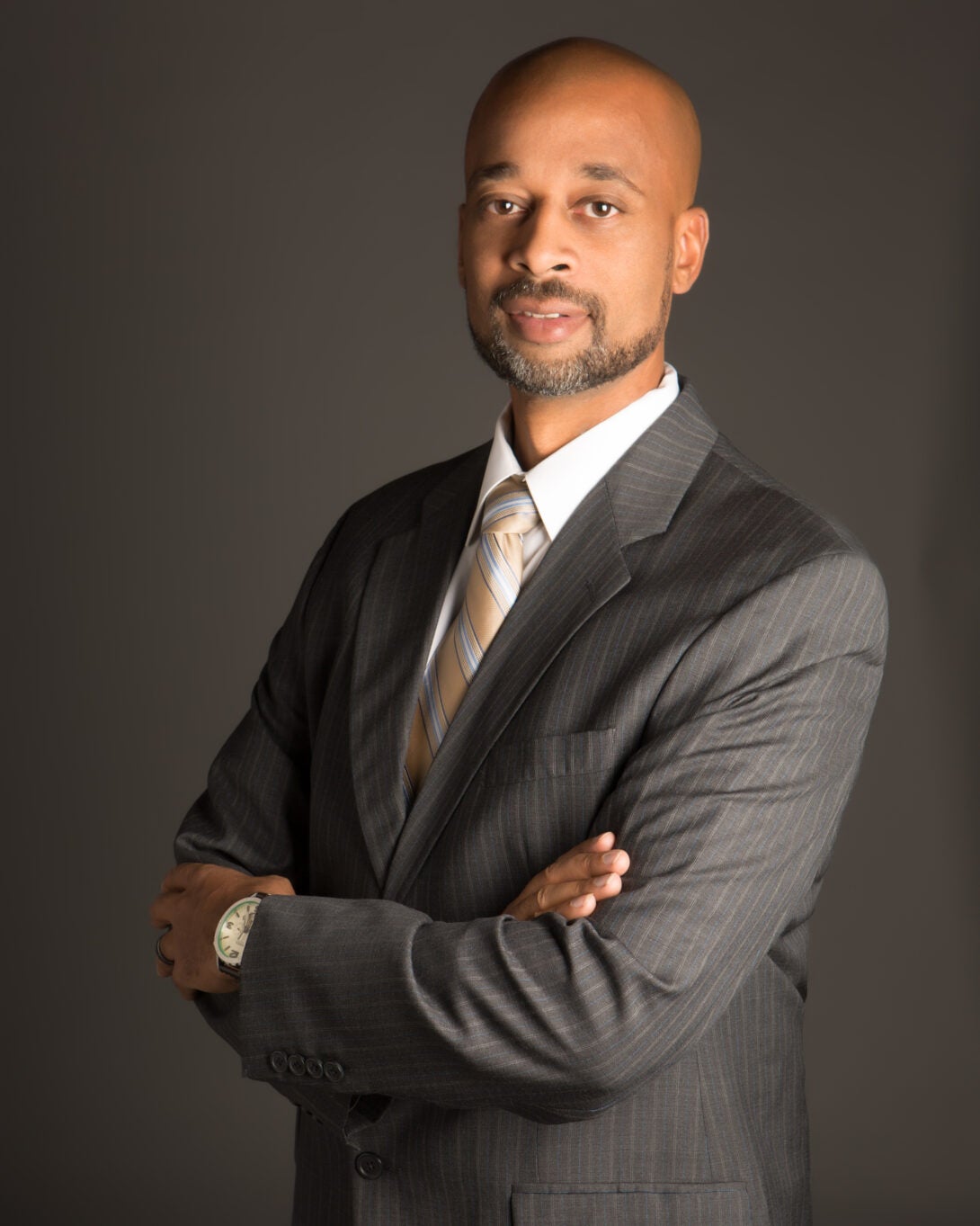 standing man with arms folded with grey jacket and white shirt looking at camera