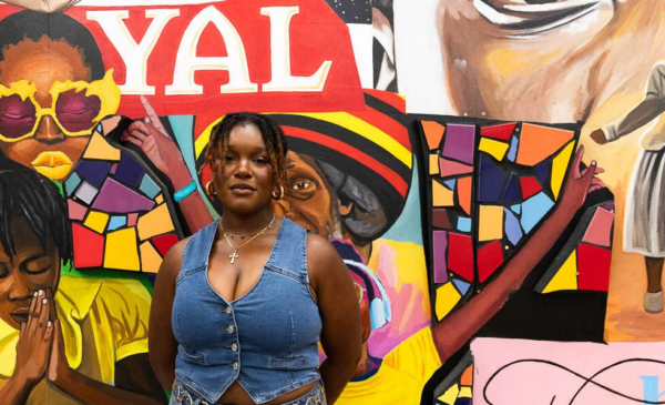 person wearing a jean vest standing in front of a mural