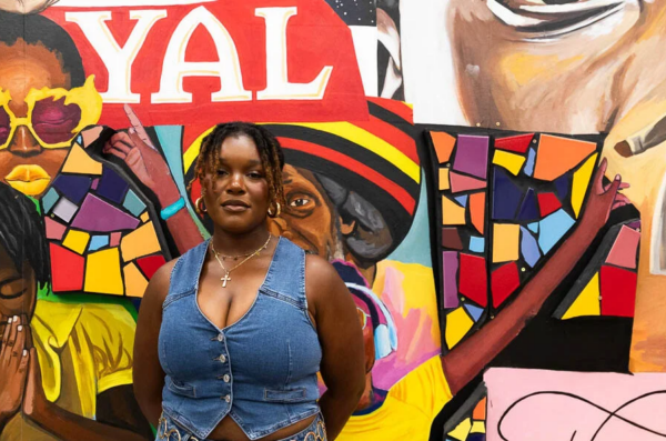 person wearing a jean vest standing in front of a mural