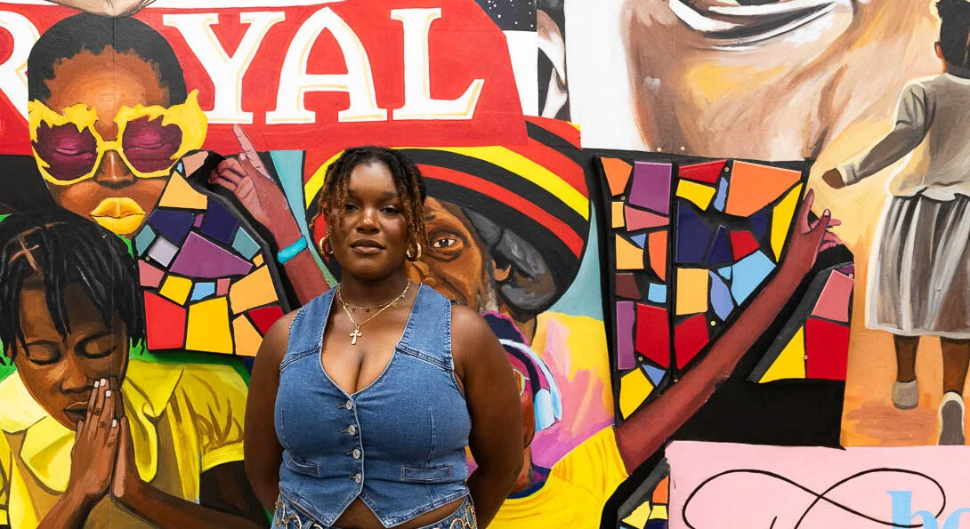 person wearing a jean vest standing in front of a mural